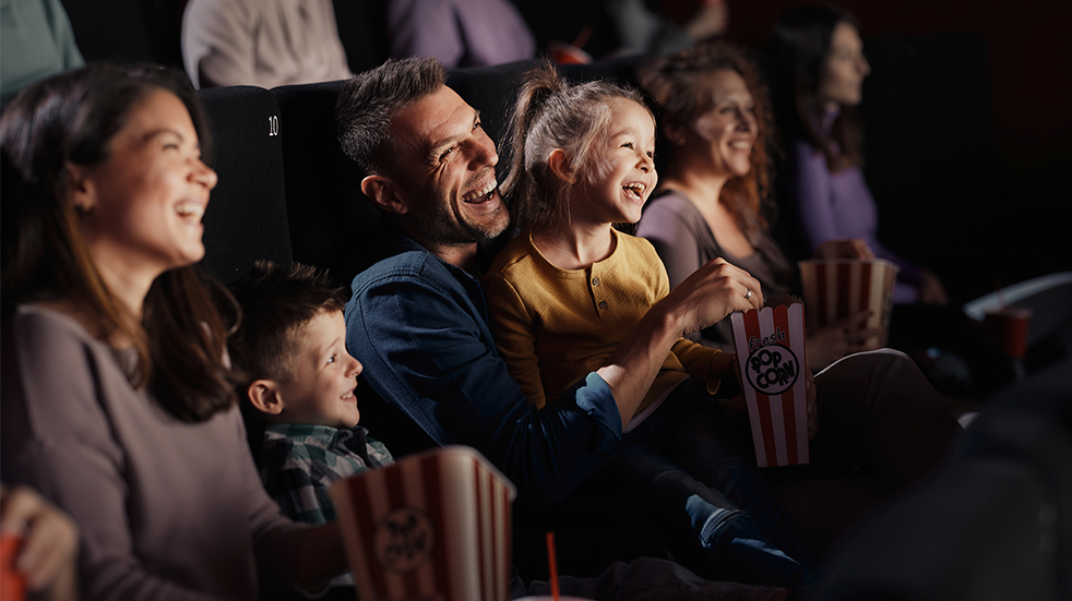 Cheerful family watching a funny movie in theatre